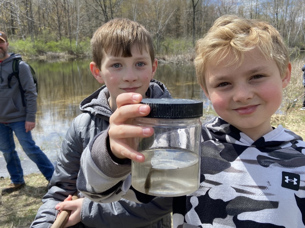 Two boys with a jar containing a fish